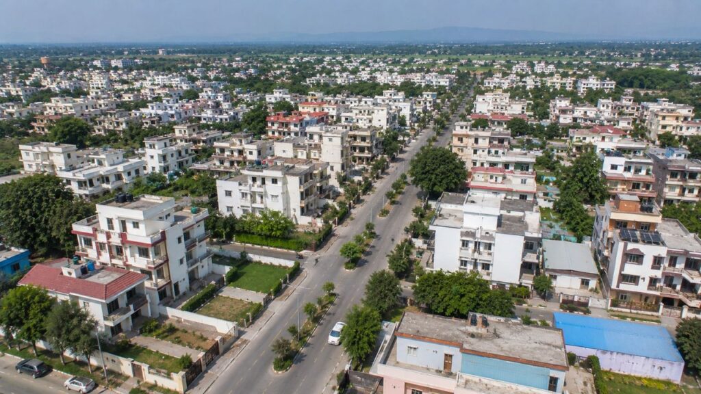Aerial view of a well-planned residential neighborhood in Rudrapur featuring wide roads, modern houses, apartment buildings, and green surroundings.
