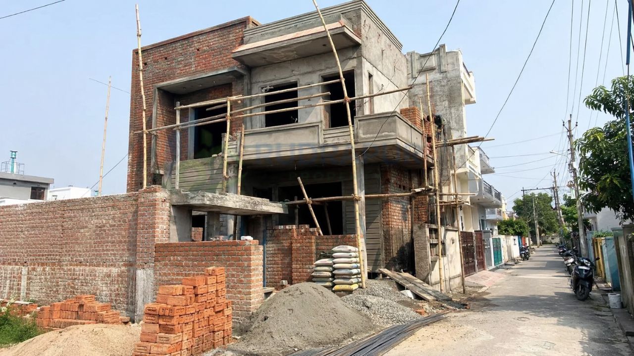 Residential house under construction in Rudrapur, Uttarakhand, showing brickwork, cement, scaffolding, and building materials for estimating house construction cost per square foot.