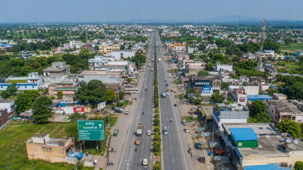 Aerial view of Kashipur Highway showing commercial buildings, residential neighborhoods, and excellent road connectivity in Kashipur, Uttarakhand.