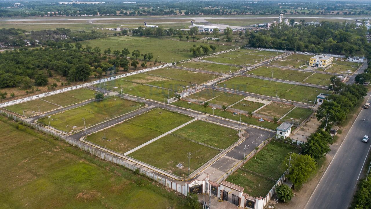 Aerial view of a gated residential plotting project near Pantnagar Airport, Rudrapur, featuring wide internal roads, boundary walls, plotted land, and excellent airport connectivity.